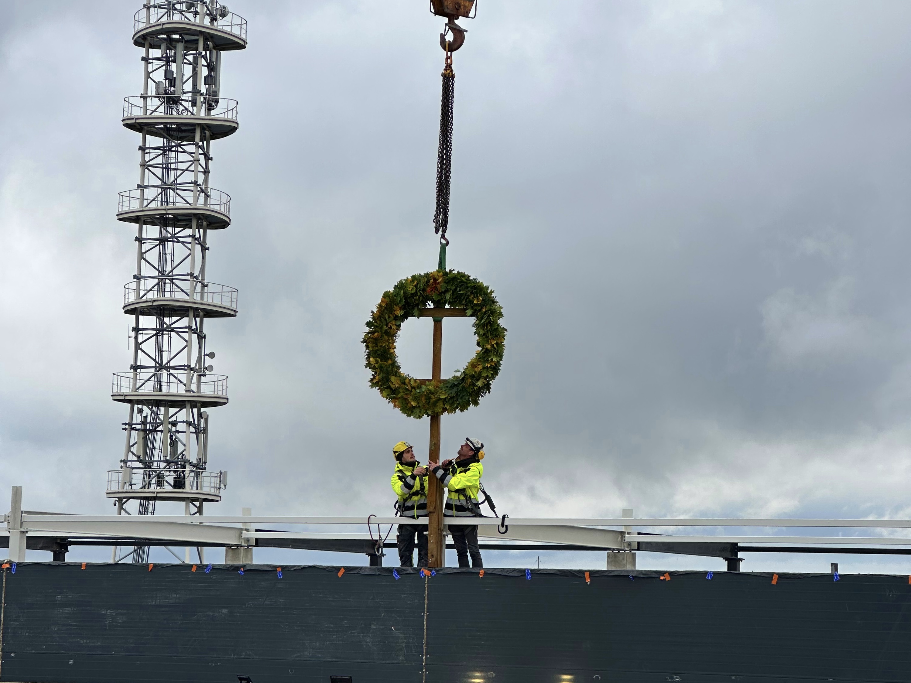 Būvnieki uzstāda spāru vainagu uz jaunbūves jumta