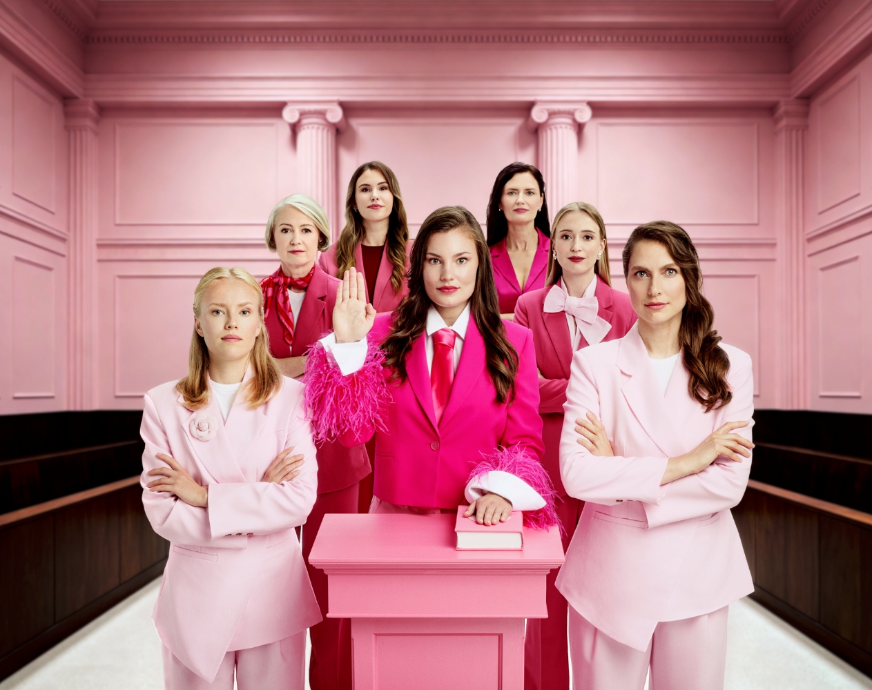 krutis Sievietes rozā kostīmos stāv tiesas zālē, simbolizējot vienotību un spēku